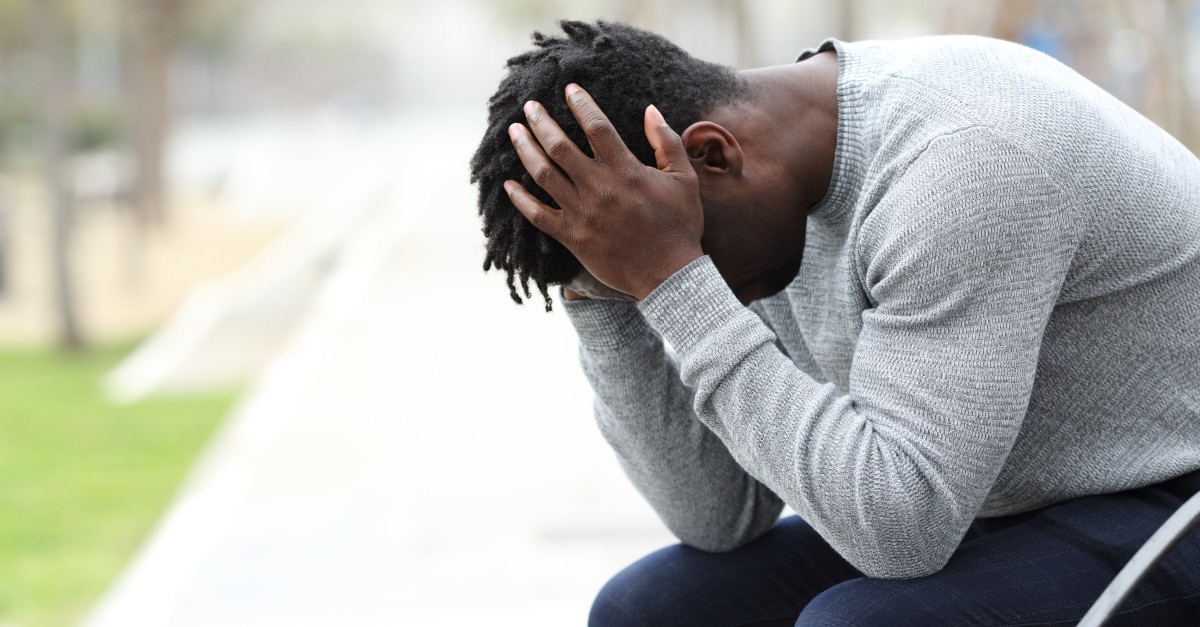 sad man overwhelmed head in hands on bench