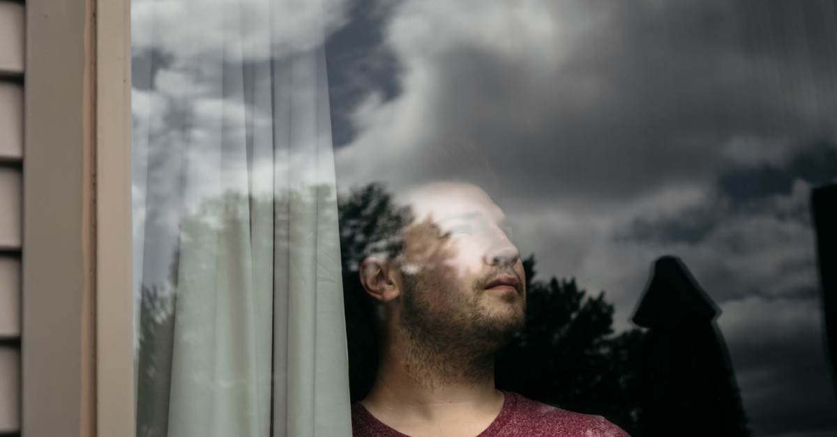 a young adult looking out a window, most millennials say they don't know what the purpose of life is