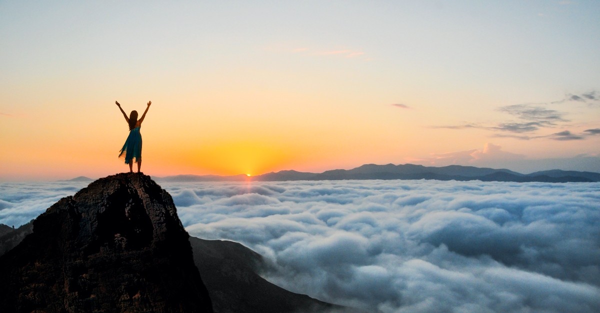 Woman on a cliff side with her arms up