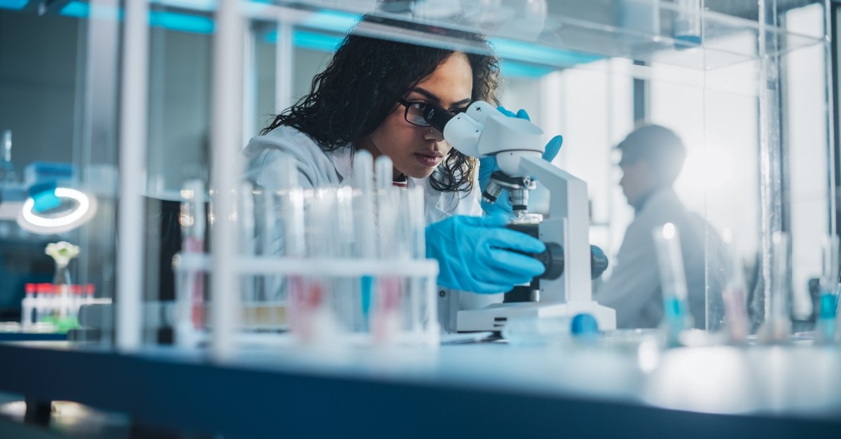 Woman scientist looking through a microscope in a lab