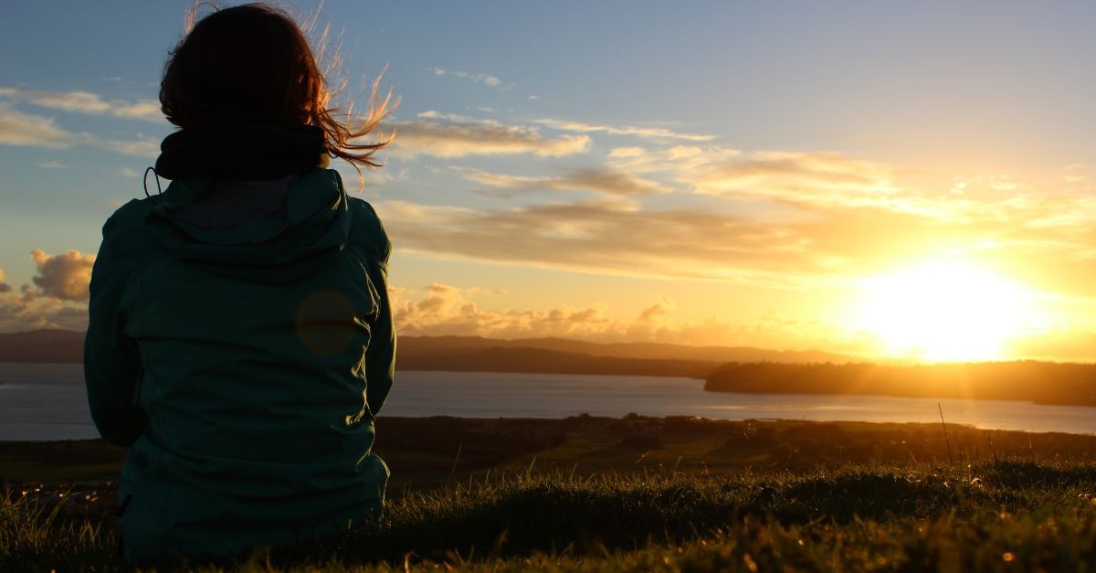 Woman watching the sunset; the difference between knowing about Jesus and knowing Him personally.