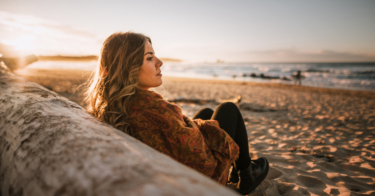 Woman sitting by the water; a prayer to stop mourning people who let you down.